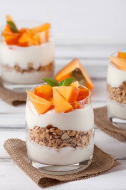 Trabzon hurması kremalı pasta ister güzel gözlük, taze olgun meyve dilimleri Beyaz ahşap zemin üzerinde. Sağlıklı vejetaryen yemek. Lezzetli tatlı. Fotoğraf kadar kapatın. Seçici odak.