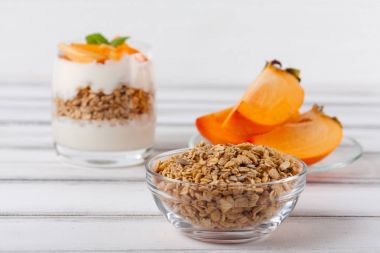 Trabzon hurması kremalı pasta ister güzel gözlük, taze olgun meyve dilimleri Beyaz ahşap zemin üzerinde. Sağlıklı vejetaryen yemek. Lezzetli tatlı. Fotoğraf kadar kapatın. Seçici odak.