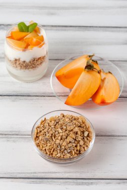 Trabzon hurması kremalı pasta ister güzel gözlük, taze olgun meyve dilimleri Beyaz ahşap zemin üzerinde. Sağlıklı vejetaryen yemek. Lezzetli tatlı. Fotoğraf kadar kapatın. Seçici odak.