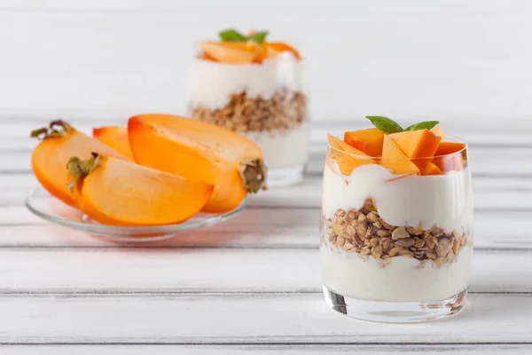 Kaki cremige Kleinigkeit in schönen Gläsern, frische reife Fruchtscheiben auf weißem Holzgrund. gesunde vegetarische Kost. leckeres Dessert. Nahaufnahmen. Selektiver Fokus. — Stockfoto