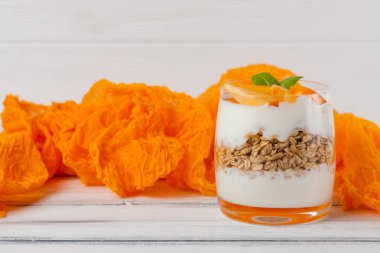 Trabzon hurması kremalı pasta ister güzel gözlük, taze olgun meyve dilimleri Beyaz ahşap zemin üzerinde. Sağlıklı vejetaryen yemek. Lezzetli tatlı. Fotoğraf kadar kapatın. Seçici odak.