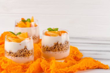 Trabzon hurması kremalı pasta ister güzel gözlük, taze olgun meyve dilimleri Beyaz ahşap zemin üzerinde. Sağlıklı vejetaryen yemek. Lezzetli tatlı. Fotoğraf kadar kapatın. Seçici odak.