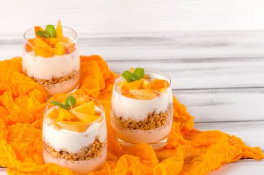 Trabzon hurması kremalı pasta ister güzel gözlük, taze olgun meyve dilimleri Beyaz ahşap zemin üzerinde. Sağlıklı vejetaryen yemek. Lezzetli tatlı. Fotoğraf kadar kapatın. Seçici odak.