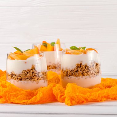 Trabzon hurması kremalı pasta ister güzel gözlük, taze olgun meyve dilimleri Beyaz ahşap zemin üzerinde. Sağlıklı vejetaryen yemek. Lezzetli tatlı. Fotoğraf kadar kapatın. Seçici odak.