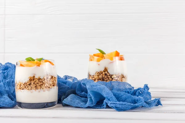 Kaki cremige Kleinigkeit in schönen Gläsern, frische reife Fruchtscheiben auf weißem Holzgrund. gesunde vegetarische Kost. leckeres Dessert. Nahaufnahmen. Selektiver Fokus. — Stockfoto