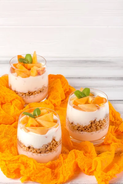Persimmon creamy trifle in beautiful glasses, fresh ripe fruit slices on white wooden background. Healthy vegetarian food. Delicious dessert. Close up photography. Selective focus. — Stock Photo, Image