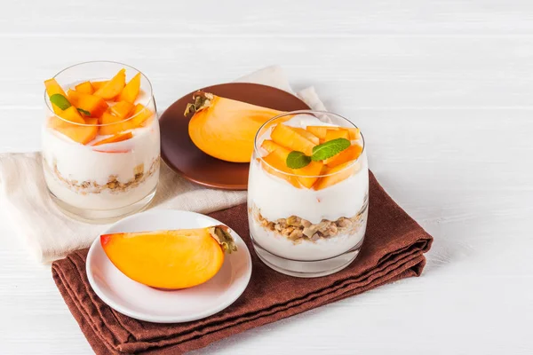 Trifle cremoso cáqui em belos copos, fatias de frutas maduras frescas no fundo de madeira branco. Comida vegetariana saudável. Deliciosa sobremesa. Fotografia de perto. Foco seletivo . — Fotografia de Stock