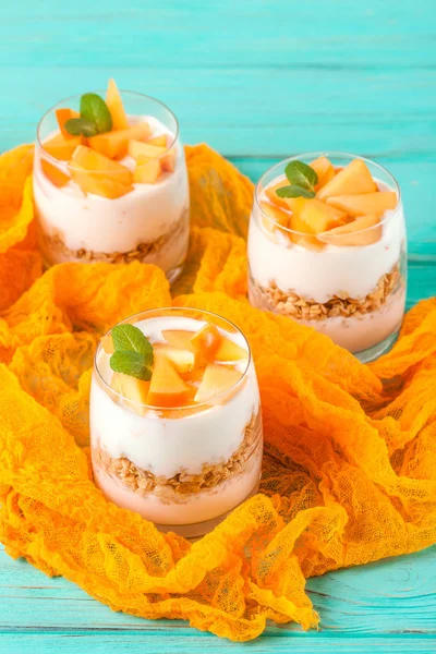 Persimmon creamy trifle in beautiful glasses, fresh ripe fruit slices on mint wooden background. Healthy vegetarian food. Delicious dessert. Close up photography. Selective focus. — Stock Photo, Image