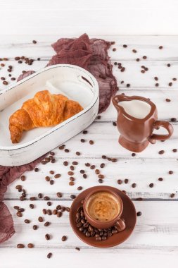 Freshly baked croissants on brown napkin, cream, to cups of coffee in ceramic dishes on white wooden background. Fresh pastries for breakfast. Delicious dessert. Closeup photography. Vertical banner clipart