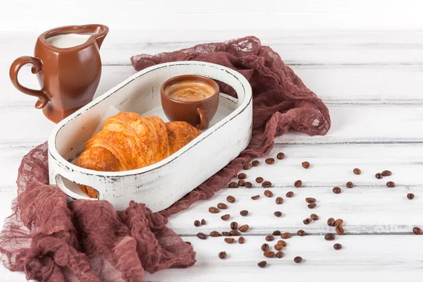 Freshly baked croissants on brown napkin, cream, to cups of coffee in ceramic dishes on white wooden background. Fresh pastries for breakfast. Delicious dessert. Closeup photography.Horizontal banner — Stock Photo, Image