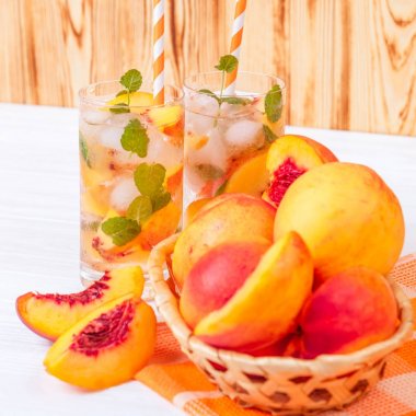 Buz ve nane yaprakları ile şeftali limonata. Ev yapımı limonata, beyaz ve turuncu olgun olgun nektarin. Şeftali çay iki kadeh. Beyaz ahşap zemin üzerinde serinletici yaz içeceği.