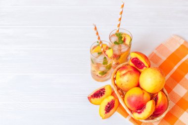 Buz ve nane yaprakları ile şeftali limonata. Ev yapımı limonata, beyaz ve turuncu olgun olgun nektarin. Şeftali çay iki kadeh. Beyaz ahşap zemin üzerinde serinletici yaz içeceği.