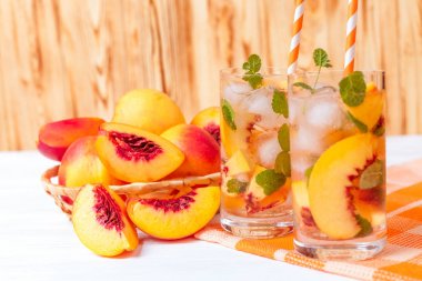 Buz ve nane yaprakları ile şeftali limonata. Ev yapımı limonata, beyaz ve turuncu olgun olgun nektarin. Şeftali çay iki kadeh. Beyaz ahşap zemin üzerinde serinletici yaz içeceği.