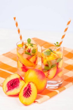 Buz ve nane yaprakları ile şeftali limonata. Ev yapımı limonata, beyaz ve turuncu olgun olgun nektarin. Şeftali çay iki kadeh. Beyaz ahşap zemin üzerinde serinletici yaz içeceği.