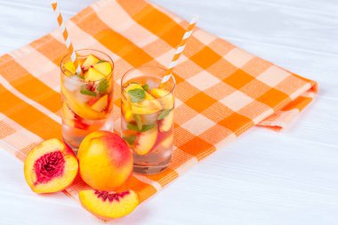 Buz ve nane yaprakları ile şeftali limonata. Ev yapımı limonata, beyaz ve turuncu olgun olgun nektarin. Şeftali çay iki kadeh. Beyaz ahşap zemin üzerinde serinletici yaz içeceği.