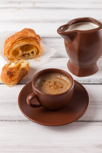 Freshly baked croissants on brown napkin, cream, to cups of coffee in ceramic dishes on white wooden background. Fresh pastries for breakfast. Delicious dessert. Closeup photography. Vertical banner — Stock Photo, Image