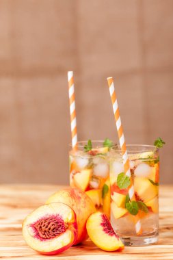 Buz ve nane yaprakları ile şeftali limonata. Ev yapımı limonata, beyaz ve turuncu olgun olgun nektarin. Şeftali çay iki kadeh. Beyaz ahşap zemin üzerinde serinletici yaz içeceği.