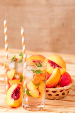 Buz ve nane yaprakları ile şeftali limonata. Ev yapımı limonata, beyaz ve turuncu olgun olgun nektarin. Şeftali çay iki kadeh. Beyaz ahşap zemin üzerinde serinletici yaz içeceği.