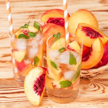 Buz ve nane yaprakları ile şeftali limonata. Ev yapımı limonata, beyaz ve turuncu olgun olgun nektarin. Şeftali çay iki kadeh. Beyaz ahşap zemin üzerinde serinletici yaz içeceği.