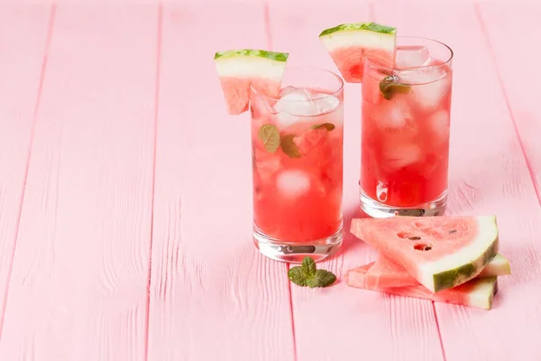 Limonada de melancia com folhas de gelo e hortelã. Limonada caseira de baga madura com rasgos vermelhos e verdes. Copo de chá de melancia fria. Bebida refrescante de verão. Cocktail em um fundo de madeira — Fotografia de Stock