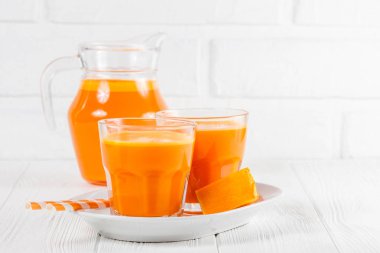 Güzel gözlük ve sürahi beyaz ahşap zemin üzerinde olgun sebze parçaları ile kabak taze meyve suyu. Tatlı portakal suyu. Sağlıklı beslenme, diyet Tema. Fotoğraf kadar kapatın. Yatay başlık