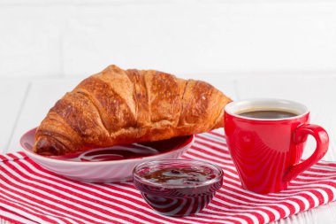 Taze pişmiş kruvasan peçete, Beyaz ahşap zemin üzerinde kırmızı Kupası kahve üzerinde. Fransız kahvaltı. Kahvaltı için taze hamur işleri. Lezzetli tatlı. Portre fotoğrafçılığı. Yatay başlık