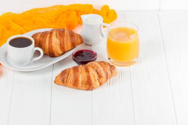 Taze pişmiş kruvasan portakal suyu, reçel, Beyaz ahşap zemin üzerinde siyah kahve. Fransız kahvaltı. Taze hamur işleri sabah için. Lezzetli tatlı. Portre fotoğrafçılığı. Yatay başlık