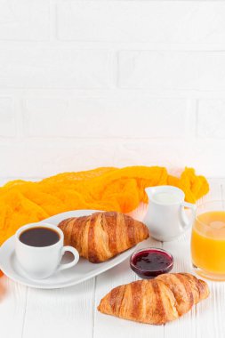 Taze pişmiş kruvasan portakal suyu, reçel, Beyaz ahşap zemin üzerinde siyah kahve. Fransız kahvaltı. Taze hamur işleri sabah için. Lezzetli tatlı. Portre fotoğrafçılığı. Dikey başlık