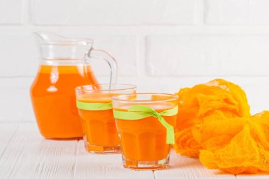 Güzel gözlük ve sürahi beyaz ahşap zemin üzerinde olgun sebze parçaları ile kabak taze meyve suyu. Tatlı portakal suyu. Sağlıklı beslenme, diyet Tema. Fotoğraf kadar kapatın. Yatay başlık