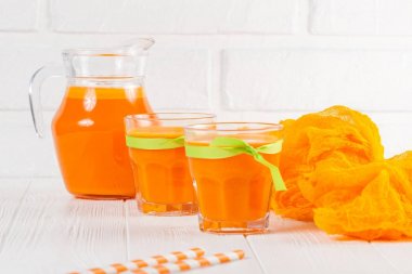 Güzel gözlük ve sürahi beyaz ahşap zemin üzerinde olgun sebze parçaları ile kabak taze meyve suyu. Tatlı portakal suyu. Sağlıklı beslenme, diyet Tema. Fotoğraf kadar kapatın. Yatay başlık