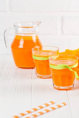 Güzel gözlük ve sürahi beyaz ahşap zemin üzerinde olgun sebze parçaları ile kabak taze meyve suyu. Tatlı portakal suyu. Sağlıklı beslenme, diyet Tema. Fotoğraf kadar kapatın. Dikey başlık