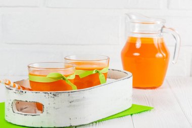 Güzel gözlük ve sürahi beyaz ahşap zemin üzerinde olgun sebze parçaları ile kabak taze meyve suyu. Tatlı portakal suyu. Sağlıklı beslenme, diyet Tema. Fotoğraf kadar kapatın. Yatay başlık