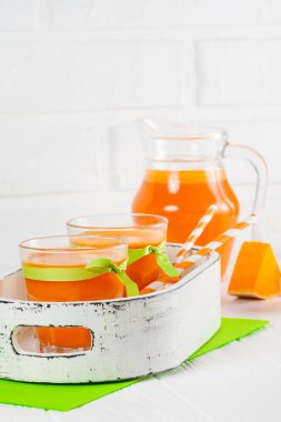 Güzel gözlük ve sürahi beyaz ahşap zemin üzerinde olgun sebze parçaları ile kabak taze meyve suyu. Tatlı portakal suyu. Sağlıklı beslenme, diyet Tema. Fotoğraf kadar kapatın. Dikey başlık