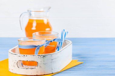 Güzel gözlük ve sürahi beyaz ahşap zemin üzerinde olgun sebze parçaları ile kabak taze meyve suyu. Tatlı portakal suyu. Sağlıklı beslenme, diyet Tema. Fotoğraf kadar kapatın. Yatay başlık