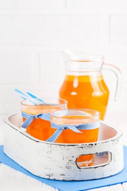 Güzel gözlük ve sürahi beyaz ahşap zemin üzerinde olgun sebze parçaları ile kabak taze meyve suyu. Tatlı portakal suyu. Sağlıklı beslenme, diyet Tema. Fotoğraf kadar kapatın. Dikey başlık