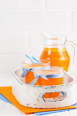 Güzel gözlük ve sürahi beyaz ahşap zemin üzerinde olgun sebze parçaları ile kabak taze meyve suyu. Tatlı portakal suyu. Sağlıklı beslenme, diyet Tema. Fotoğraf kadar kapatın. Dikey başlık