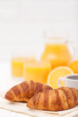 Taze pişmiş kruvasan, portakal suyu, taze meyve, kahve Beyaz ahşap zemin üzerinde. Fransız kahvaltı. Taze hamur işleri sabah için. Lezzetli tatlı. Portre fotoğrafçılığı. Dikey başlık