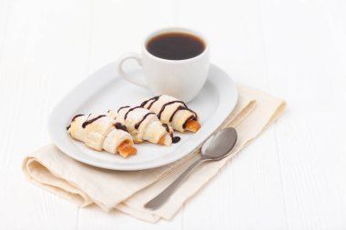 Fırından yeni çıkmış kruvasan, reçel, Beyaz ahşap zemin üzerinde siyah kahve. Ev yapımı kurabiye. Kahvaltı için taze hamur işleri. Lezzetli tatlı. Portre fotoğrafçılığı. Yatay başlık