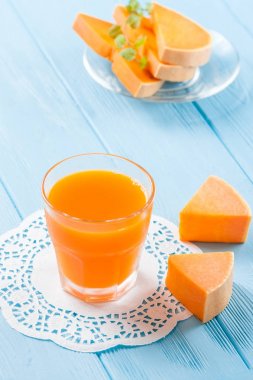 Güzel gözlük ve sürahi beyaz ahşap zemin üzerinde olgun sebze parçaları ile kabak taze meyve suyu. Tatlı portakal suyu. Sağlıklı beslenme, diyet Tema. Fotoğraf kadar kapatın. Dikey başlık