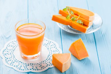 Güzel gözlük ve sürahi beyaz ahşap zemin üzerinde olgun sebze parçaları ile kabak taze meyve suyu. Tatlı portakal suyu. Sağlıklı beslenme, diyet Tema. Fotoğraf kadar kapatın. Yatay başlık