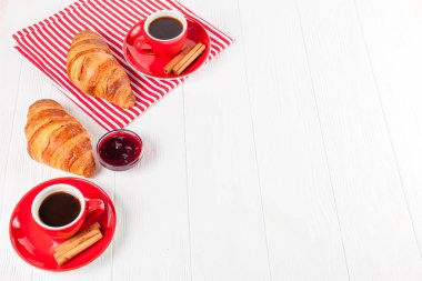 Taze pişmiş kruvasan peçete, Beyaz ahşap zemin üzerinde kırmızı Kupası kahve üzerinde. Fransız kahvaltı. Kahvaltı için taze hamur işleri. Lezzetli tatlı. Portre fotoğrafçılığı. Yatay başlık