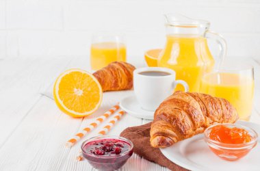 Fırından yeni çıkmış kruvasan, portakal suyu, taze meyve, Beyaz ahşap arka plan üzerinde reçel. Fransız kahvaltı. Taze hamur işleri sabah için. Lezzetli tatlı. Portre fotoğrafçılığı. Yatay başlık