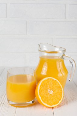 Cam ve sürahi, yarısı Beyaz ahşap zemin üzerinde narenciye taze portakal suyu. Sağlıklı beslenme, diyet Tema. Sulu meyve. Portre fotoğrafçılığı. Dikey başlık