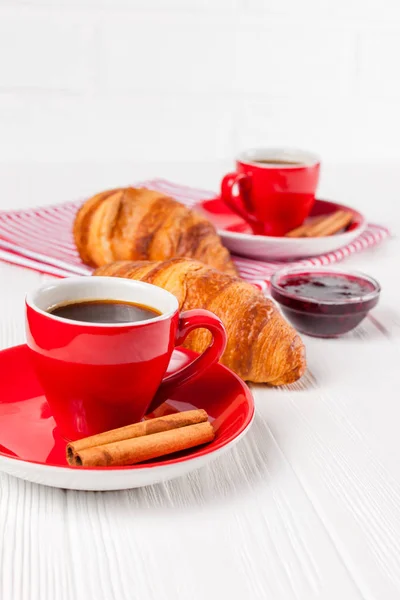 Freshly baked croissant on napkin, cup of coffee in red cup on white wooden background. French breakfast. Fresh pastries for breakfast. Delicious dessert. Closeup photography. Vertical banner — Stock Photo, Image
