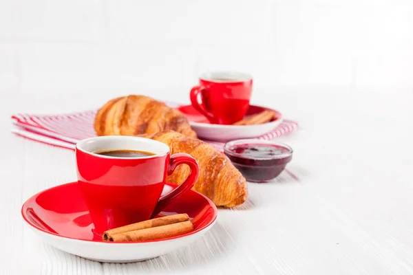 Freshly baked croissant on napkin, cup of coffee in red cup on white wooden background. French breakfast. Fresh pastries for breakfast. Delicious dessert. Closeup photography. Horizontal banner — Stock Photo, Image