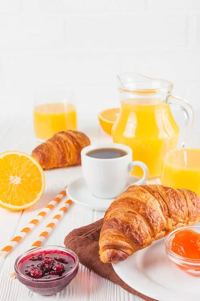 Croissant recién horneado, zumo de naranja, frutas frescas, mermelada sobre fondo de madera blanca. Desayuno francés. Pasteles frescos para la mañana. Delicioso postre. Fotografía de cerca. Banner vertical —  Fotos de Stock