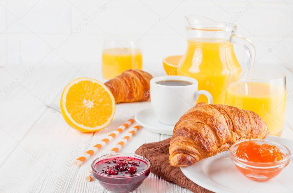 Freshly baked croissant, orange juice, fresh fruits, jam on white wooden background. French breakfast. Fresh pastries for morning. Delicious dessert. Closeup photography. Horizontal banner