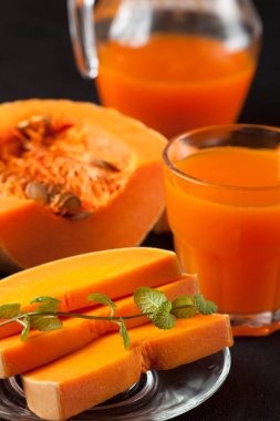 Güzel gözlük ve sürahi kahverengi ahşap zemin üzerinde olgun sebze parçaları ile kabak taze meyve suyu. Tatlı portakal suyu. Sağlıklı beslenme, diyet Tema. Fotoğraf kadar kapatın. Dikey başlık