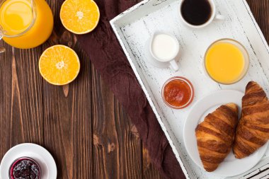 Fırından yeni çıkmış kruvasan, portakal suyu, taze meyve, kahverengi ahşap arka plan üzerinde reçel. Fransız kahvaltı. Taze hamur işleri sabah için. Lezzetli tatlı. Üstten Görünüm. Portre fotoğrafçılığı. Yatay başlık