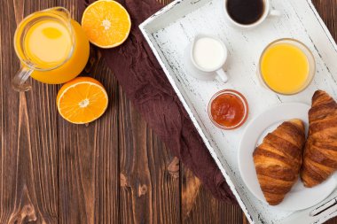 Fırından yeni çıkmış kruvasan, portakal suyu, taze meyve, kahverengi ahşap arka plan üzerinde reçel. Fransız kahvaltı. Taze hamur işleri sabah için. Lezzetli tatlı. Üstten Görünüm. Portre fotoğrafçılığı. Yatay başlık